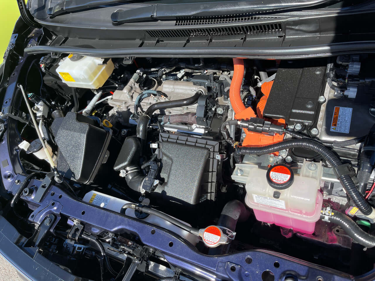 Engine compartment of 2015 Toyota Voxy 1.8L Hybrid V Premium Edition showing hybrid components and layout.