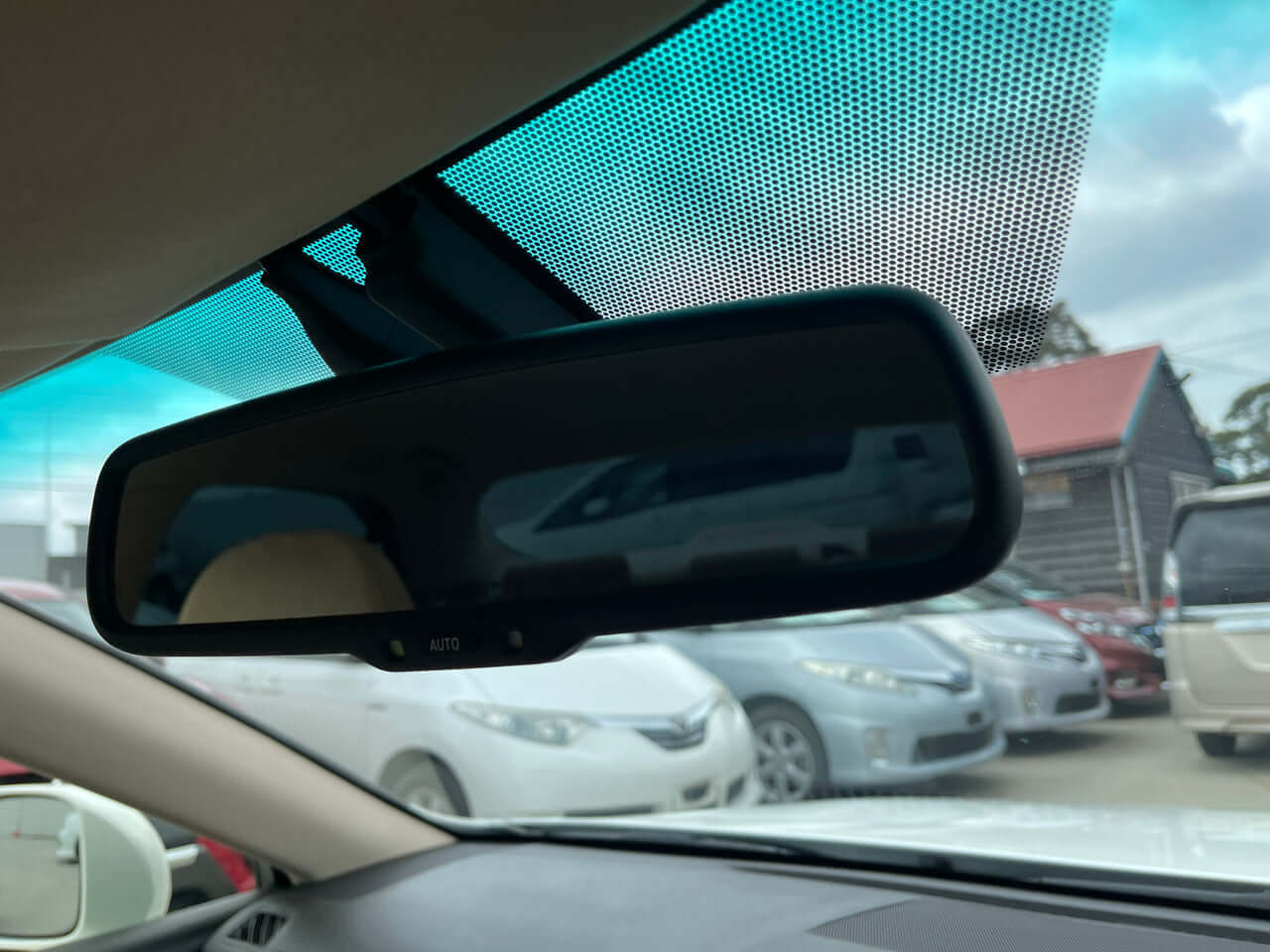 2012 Toyota Crown Majesta V8 4.6L Interior view of the rearview mirror in a sedan, reflecting outside vehicles and car cabin details.