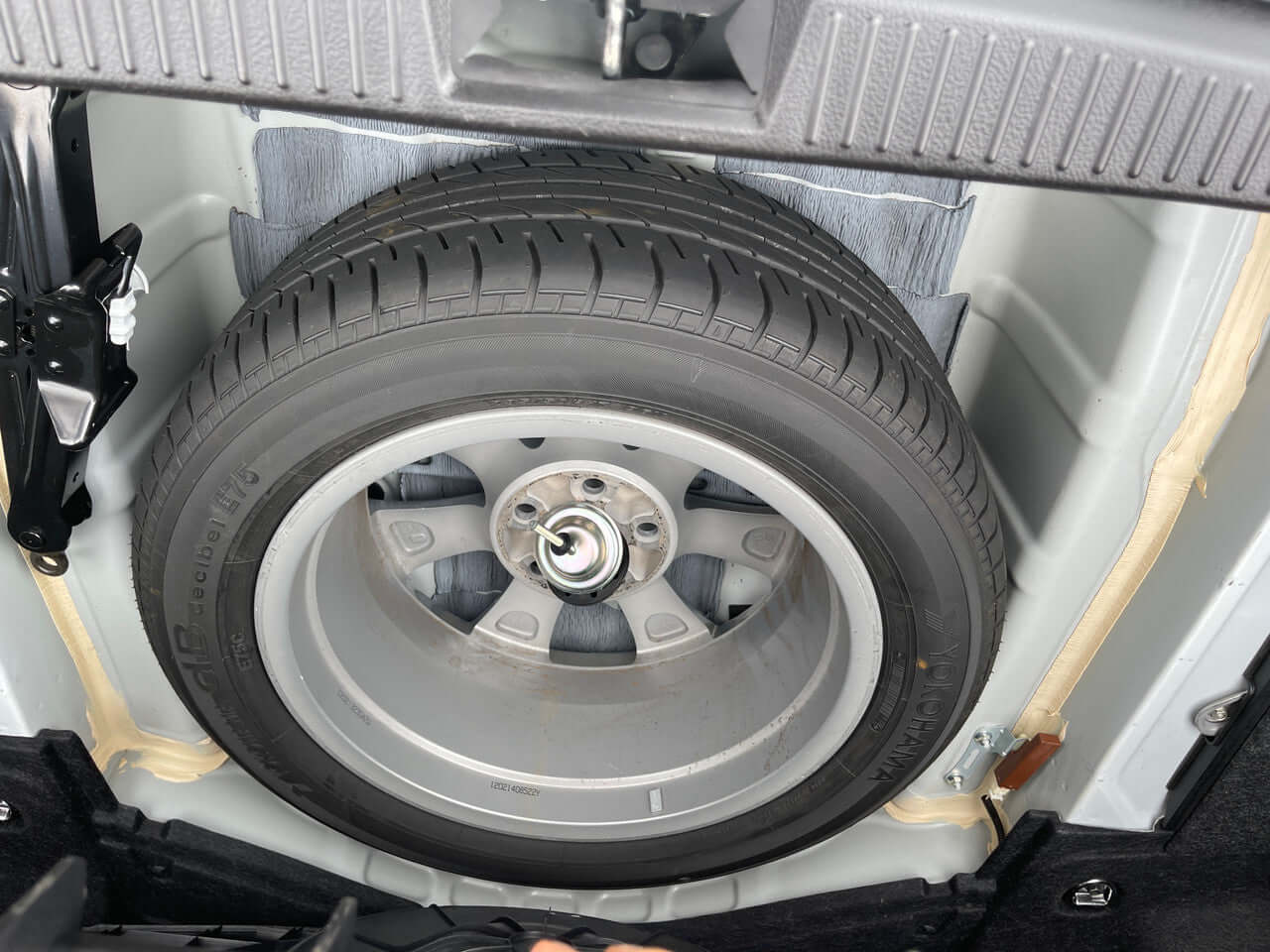 2012 Toyota Crown Majesta V8 4.6L spare tire in trunk, showing wheel design and storage area.