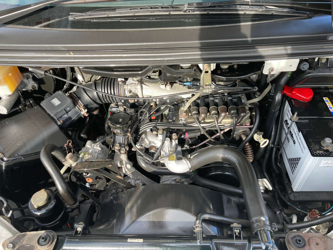 Engine compartment of 2005 Mitsubishi Delica Space Gear V6 3.0L 4WD showcasing its components and wiring.