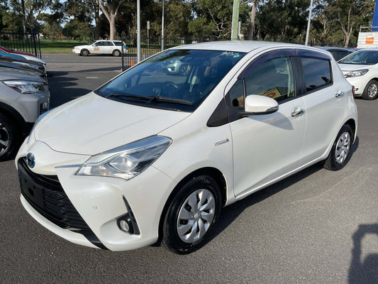 2019 Toyota Vitz 1.5L Hybrid parked on street with clear sky, showcasing exterior design and features.