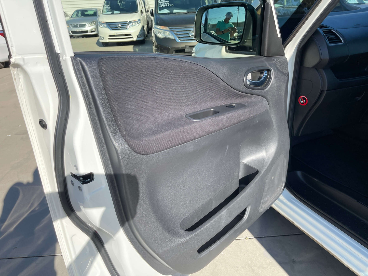 Interior view of the door panel of a 2015 Nissan Serena 2.0L S-Hybrid showcasing black fabric and control features.