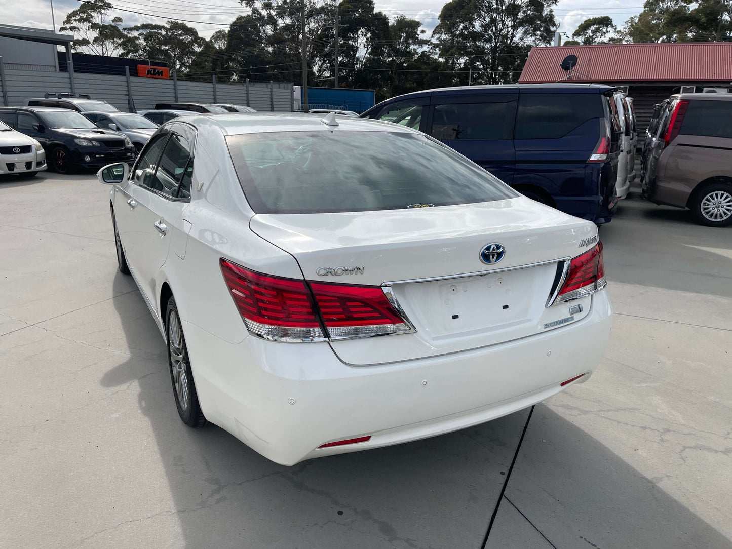 Rear view of a 2014 Toyota Crown Majesta V6 3.5L Hybrid Luxury Sedan in white color, showcasing its sleek design and alloy wheels.