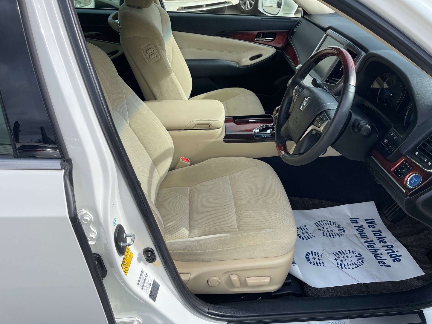 Interior view of a 2014 Toyota Crown Majesta V6 3.5L Hybrid Luxury Sedan showing its beige seats and dashboard.