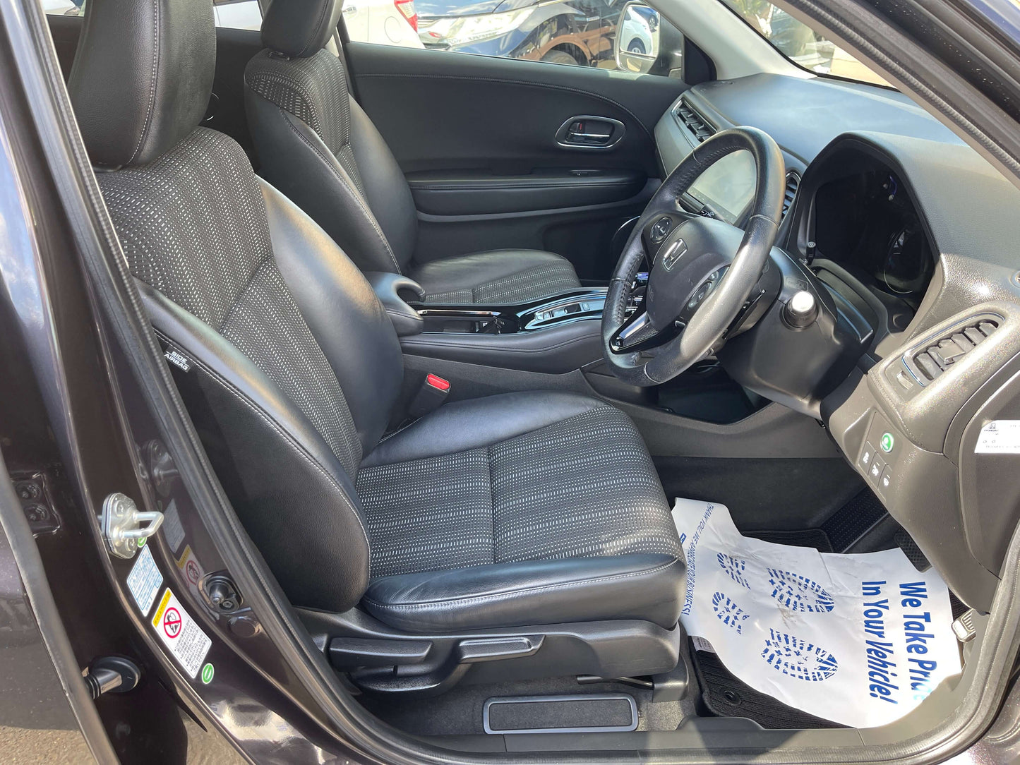 Interior of a 2014 Honda Vezel HR-V Hybrid Z SUV showcasing black leather seating and modern dashboard.