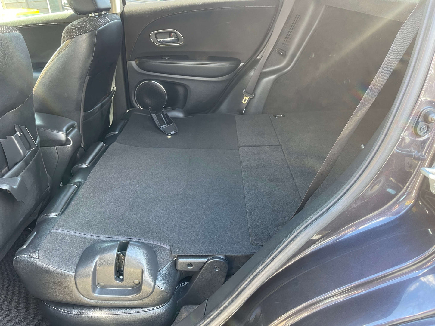 Interior view of the rear seats in the 2014 Honda Vezel HR-V Hybrid with flat-folded seating for extra cargo space.