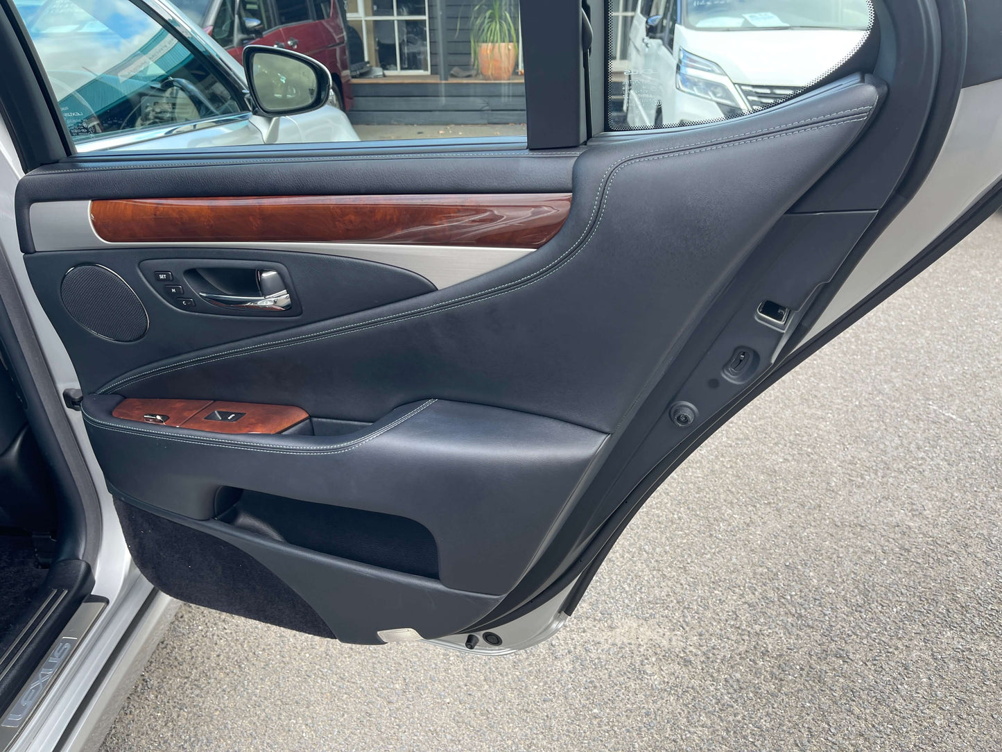 Interior view of the door panel from a 2015 Lexus LS460 AWD V8 4.6L, showcasing luxury finishes and controls.