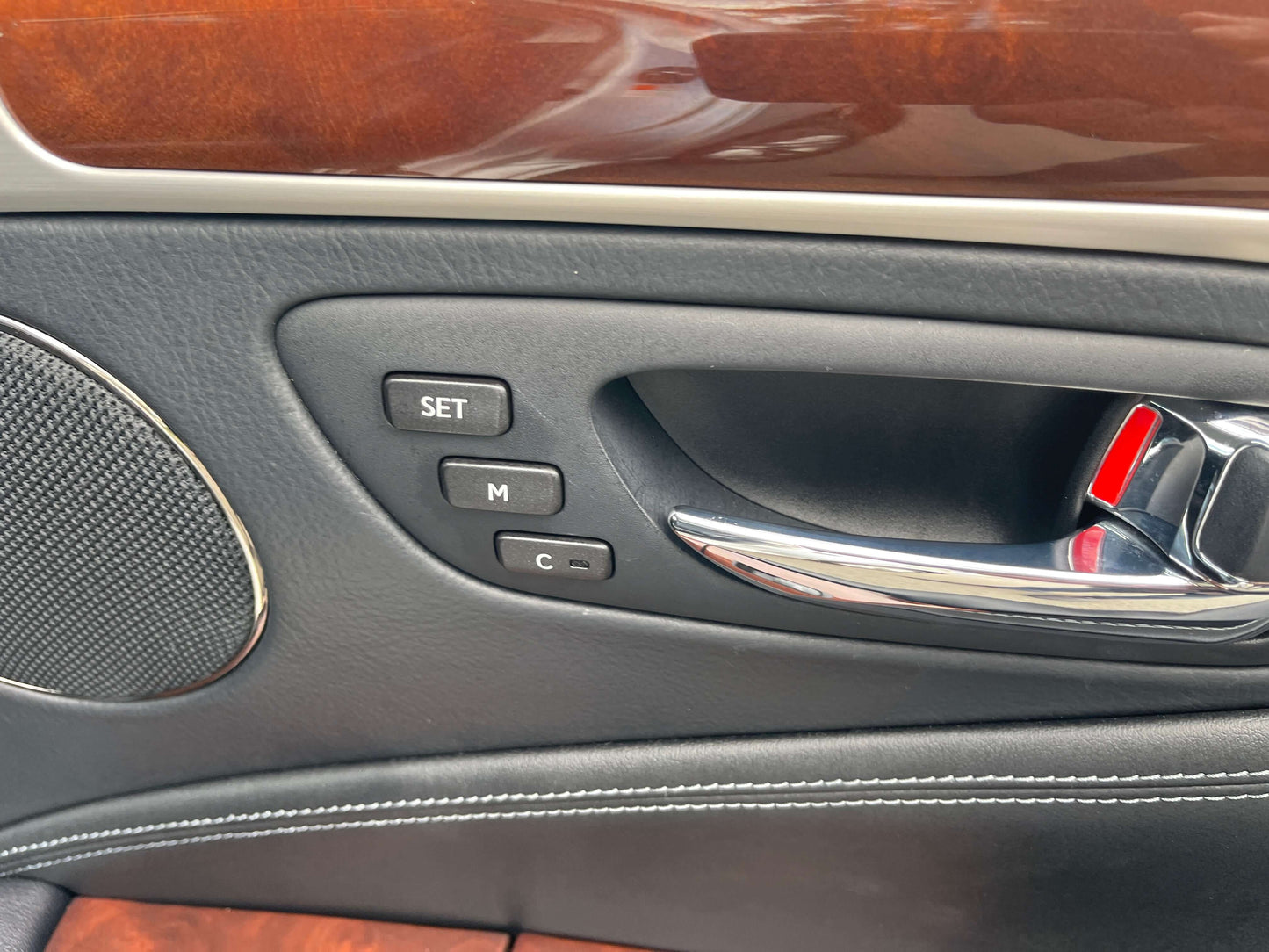 Interior door panel of 2015 Lexus LS460 AWD V8 4.6L showing seat memory buttons and silver door handle.