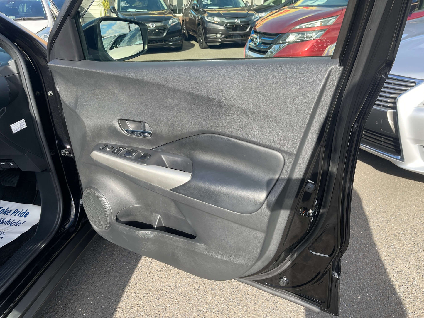 Interior view of the 2020 Nissan Kicks e-Power X Edition driver's side door panel with controls and window view.