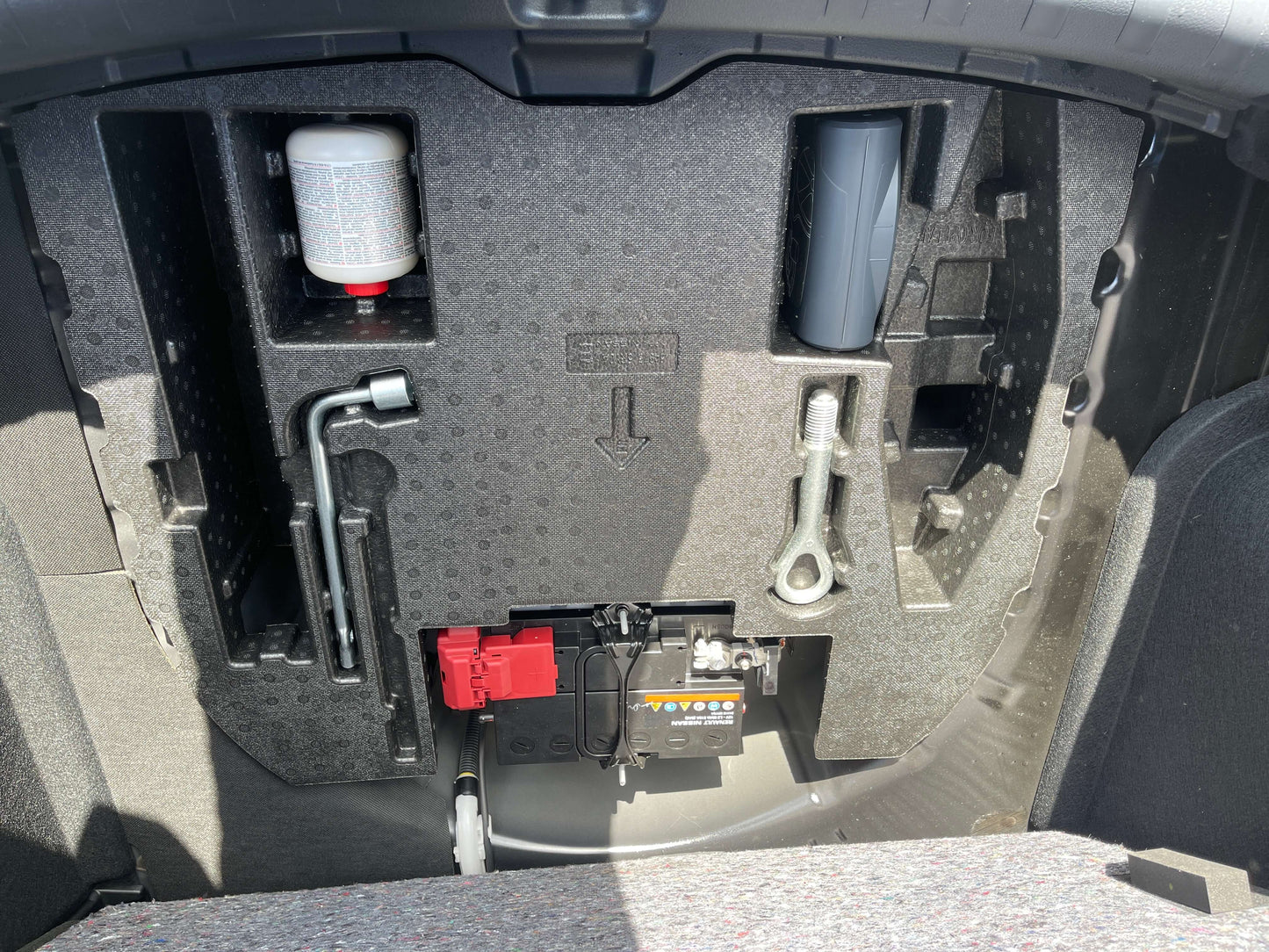 Storage compartment of the 2020 Nissan Kicks e-Power X Edition showing tools and battery.
