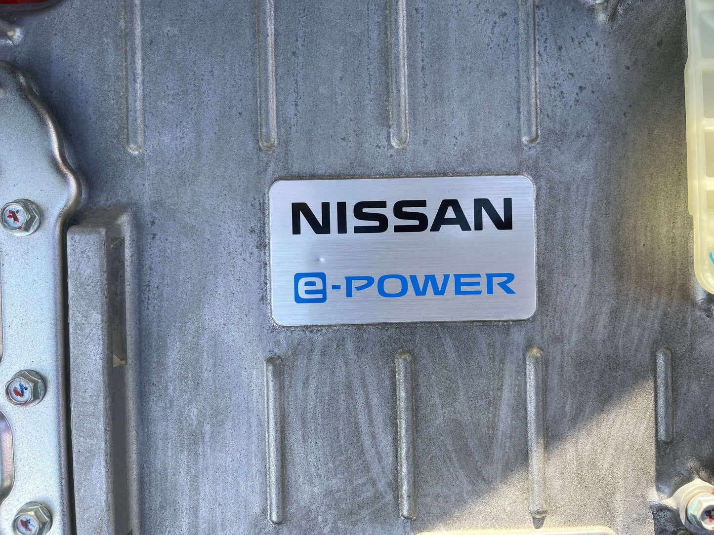 Nissan e-Power emblem on the engine of a 2020 Nissan Kicks e-Power, showcasing advanced hybrid technology.
