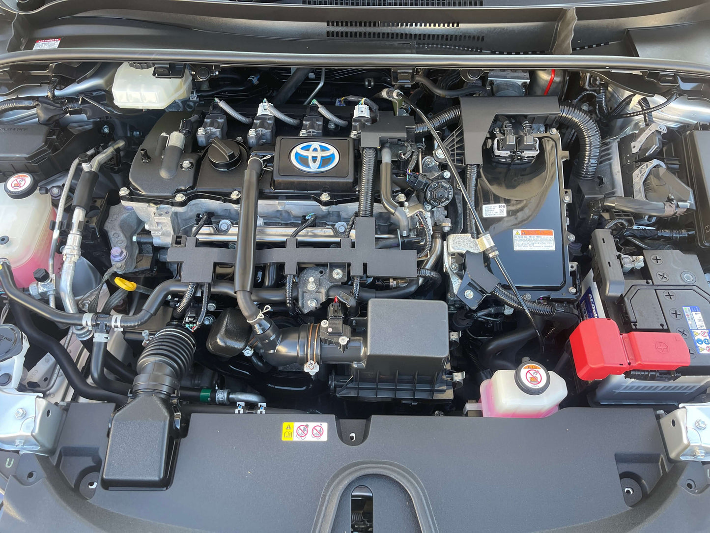 Engine bay of a 2019 Toyota Corolla Touring 1.8 4WD Hybrid G-X showing components and battery.