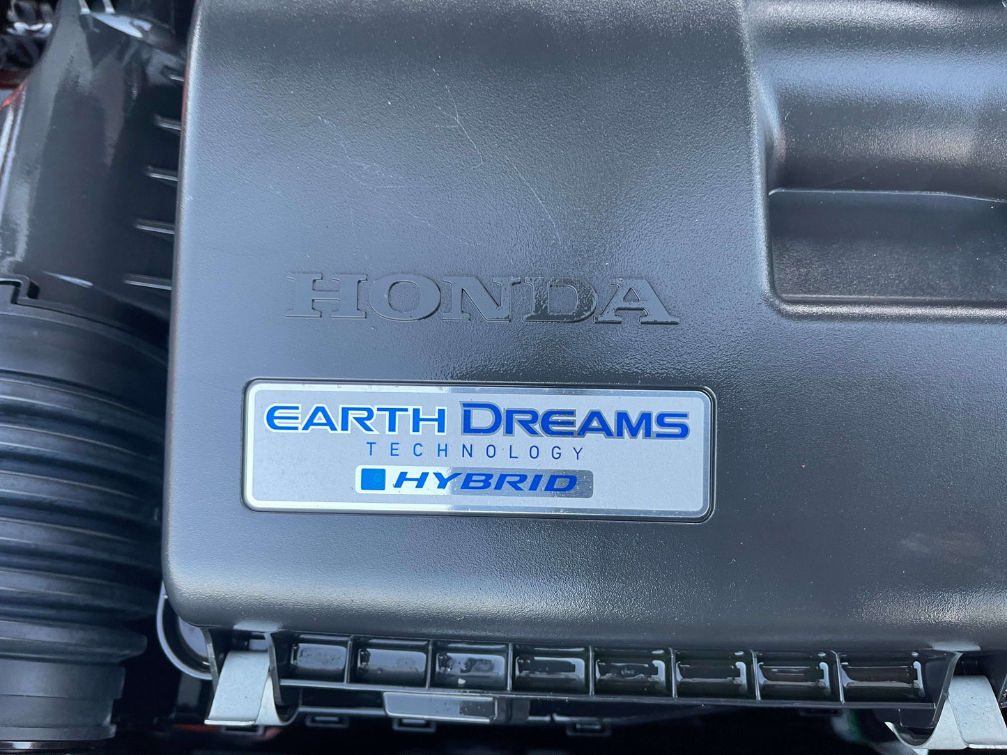 2020 Honda Fit 1.5 eHEV Close-up of the Honda engine cover with Earth Dreams Technology label, showcasing hybrid features.