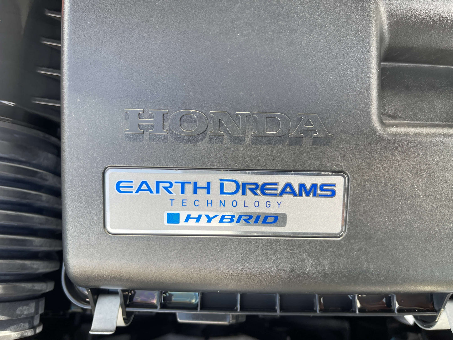 Image of Honda Earth Dreams Technology badge on a hybrid engine, emphasizing efficiency and innovation in the 2020 Honda Fit 1.5 eHEV Home Edition.