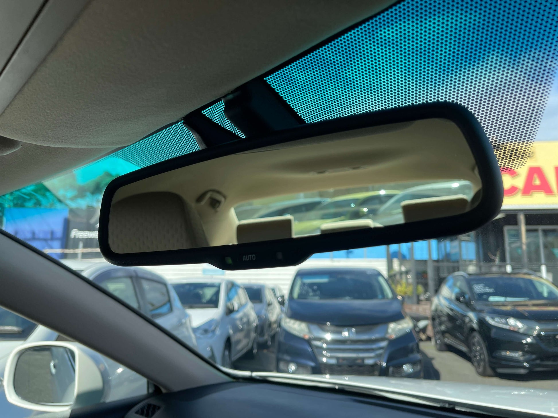 2008 Toyota Crown V6 3.0L Interior view of a car's rearview mirror showing cars parked in the background.