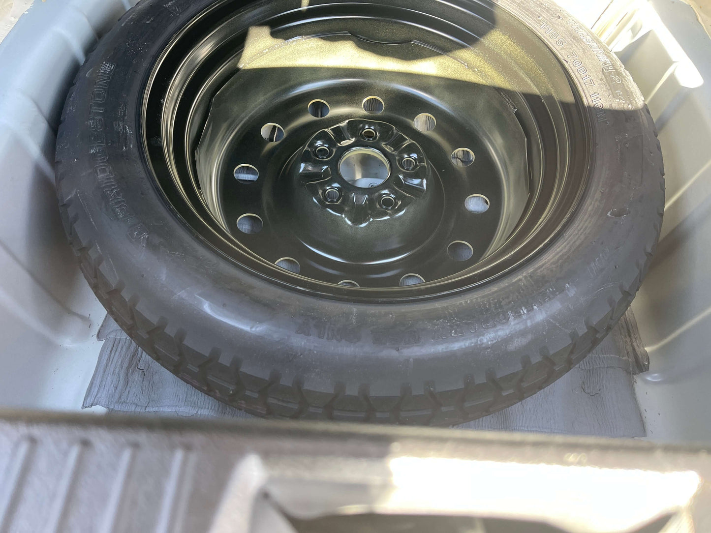 2008 Toyota Crown V6 3.0L spare tire inside trunk compartment, featuring a black wheel and tire, essential for road safety.