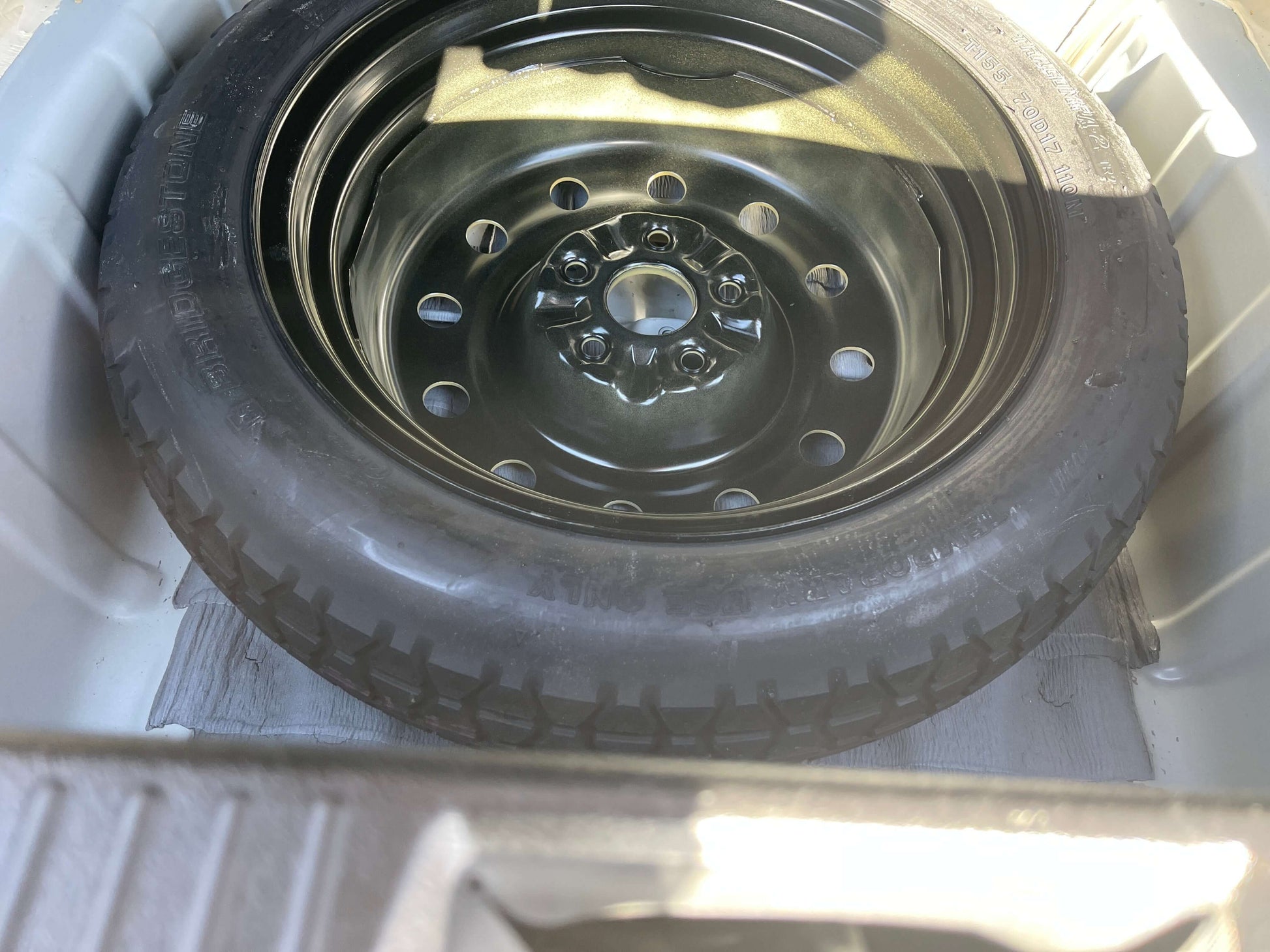 2008 Toyota Crown V6 3.0L spare tire inside trunk compartment, featuring a black wheel and tire, essential for road safety.