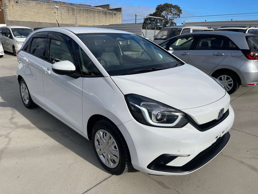 2020 Honda Fit 1.5 eHEV Home Edition in white, showcasing a hybrid hatchback design, parked outdoors.