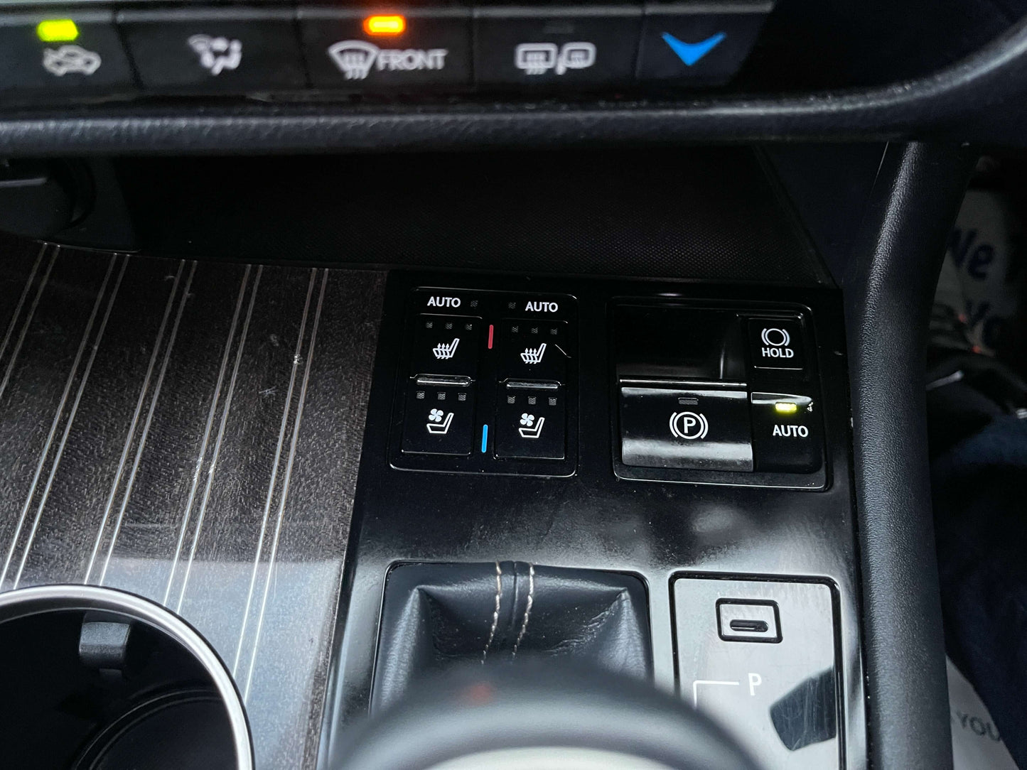 Close-up of 2017 Lexus RX450H control panel with heated seat buttons and electronic parking brake.