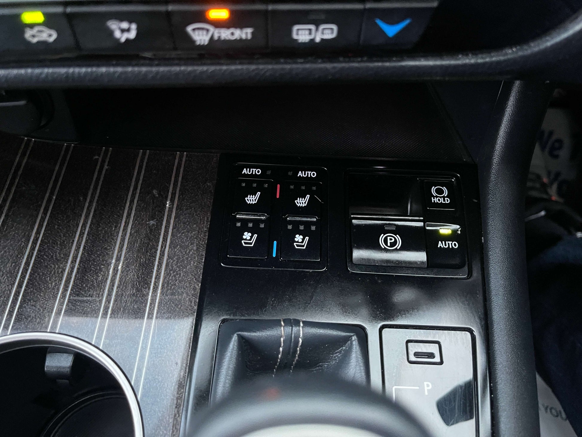Close-up of 2017 Lexus RX450H control panel with heated seat buttons and electronic parking brake.