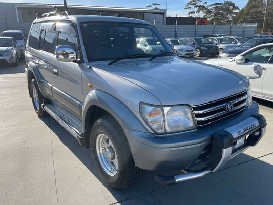 1996 Toyota Land Cruiser Prado V6 3.4L parked, showcasing its robust design and silver exterior.