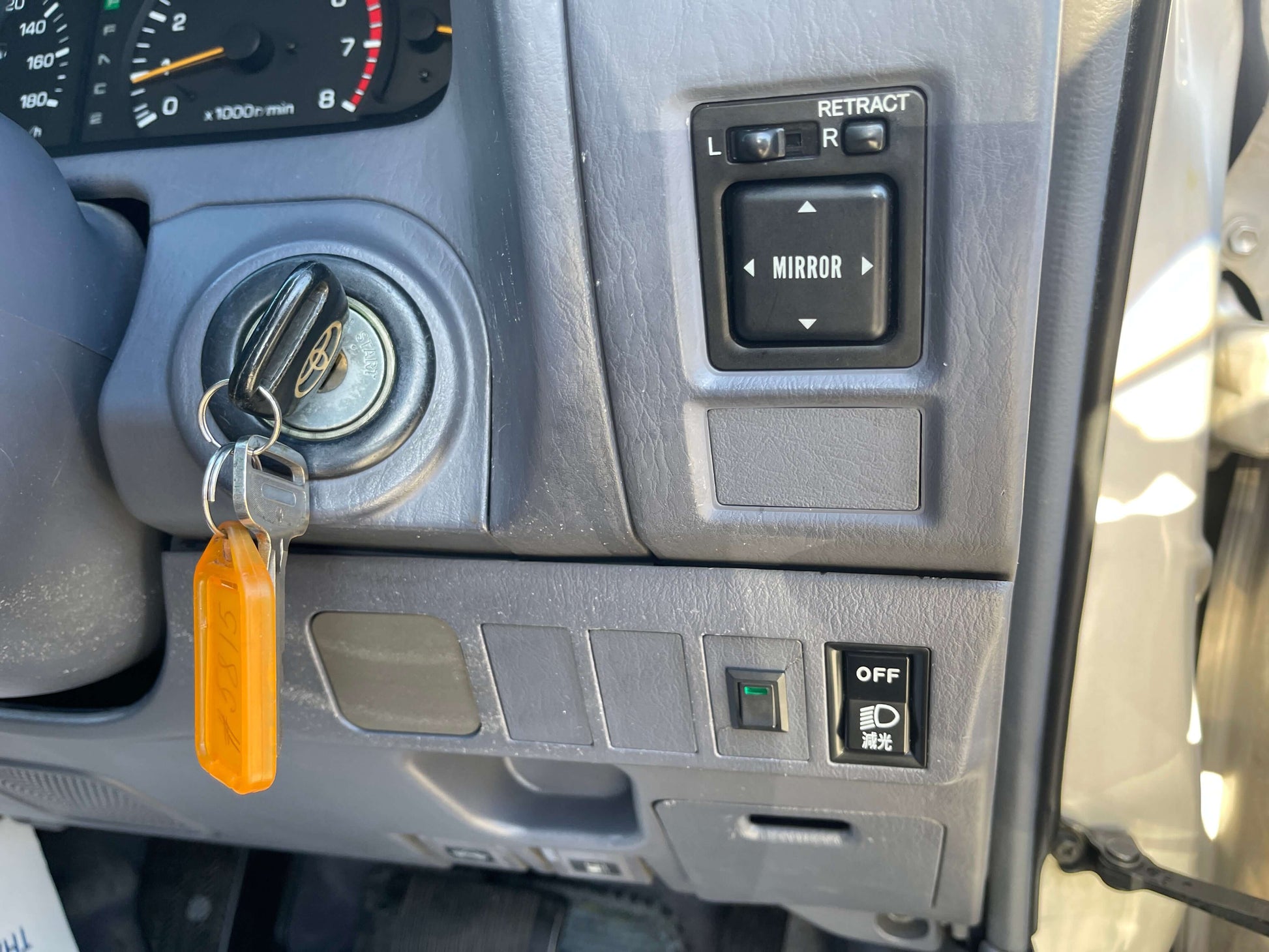 Interior controls of a 1996 Toyota Land Cruiser Prado V6 3.4L, showing key ignition and mirror adjustment buttons.