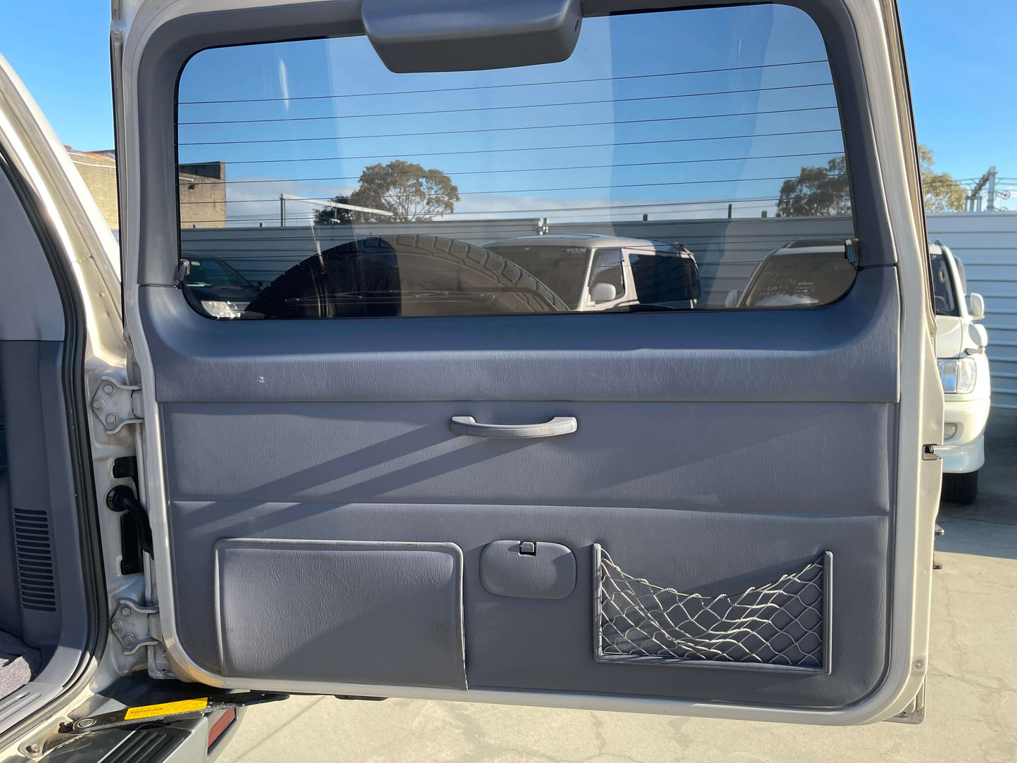 Interior door panel of a 1996 Toyota Land Cruiser Prado V6 3.4L TZ showcasing storage and window.
