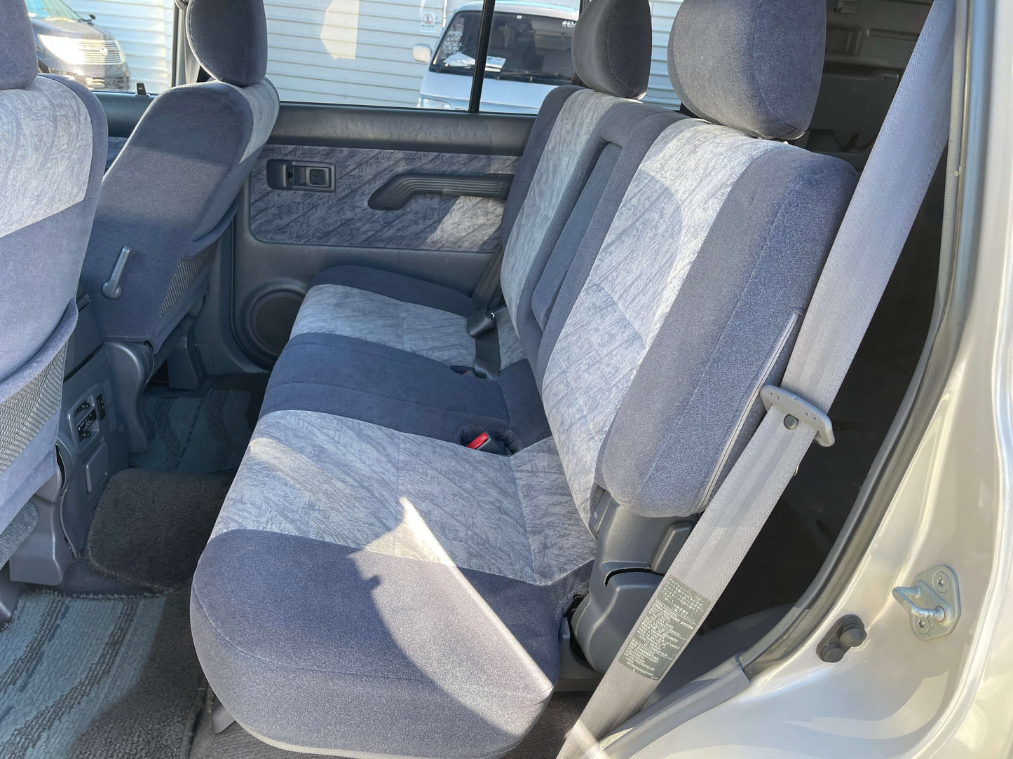 Interior of a 1996 Toyota Land Cruiser Prado V6 3.4L showing spacious back seats with gray upholstery.