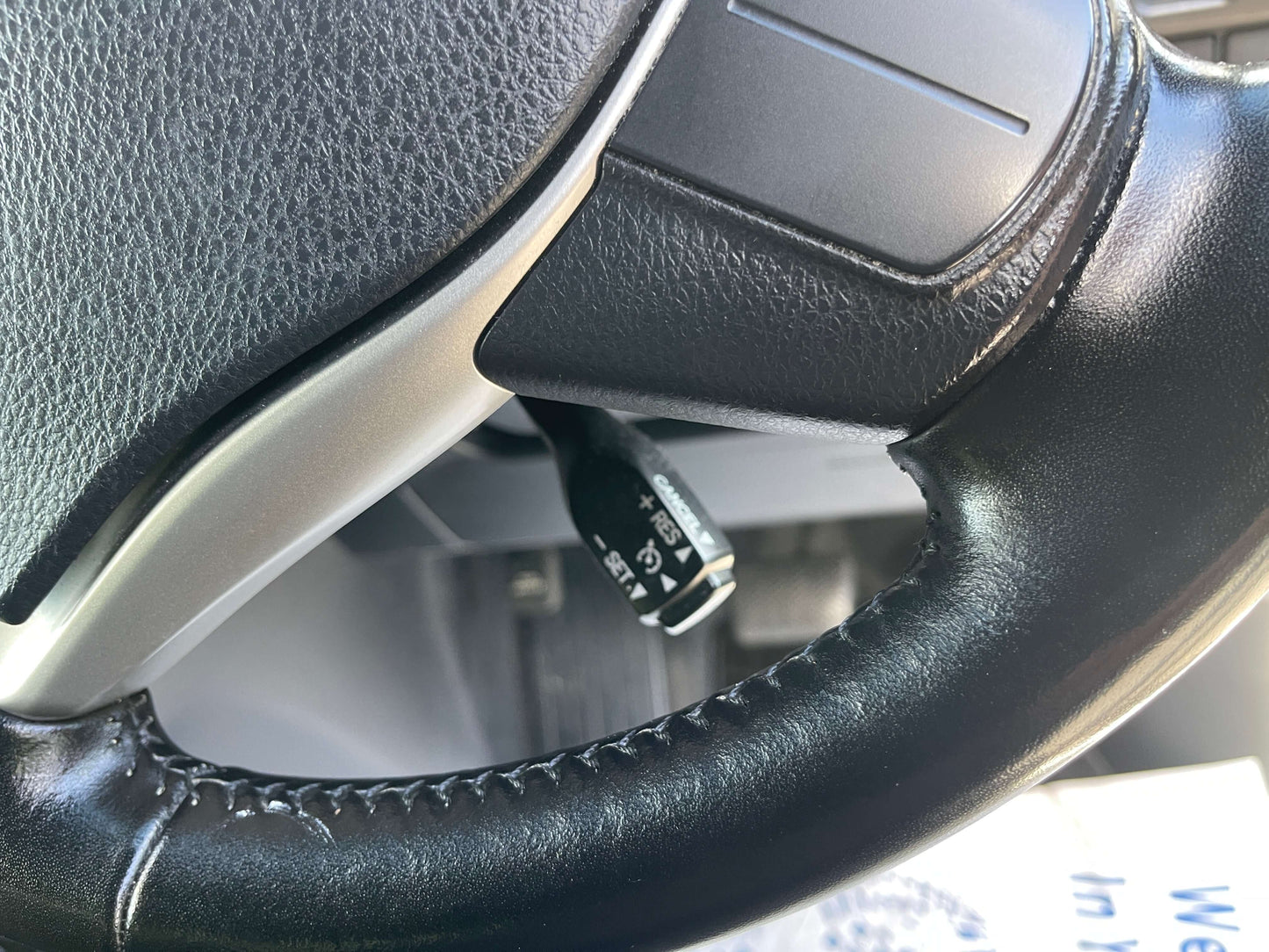Close-up of 2018 Toyota Noah 1.8L Hybrid steering wheel with control lever, promoting driving comfort and technology.