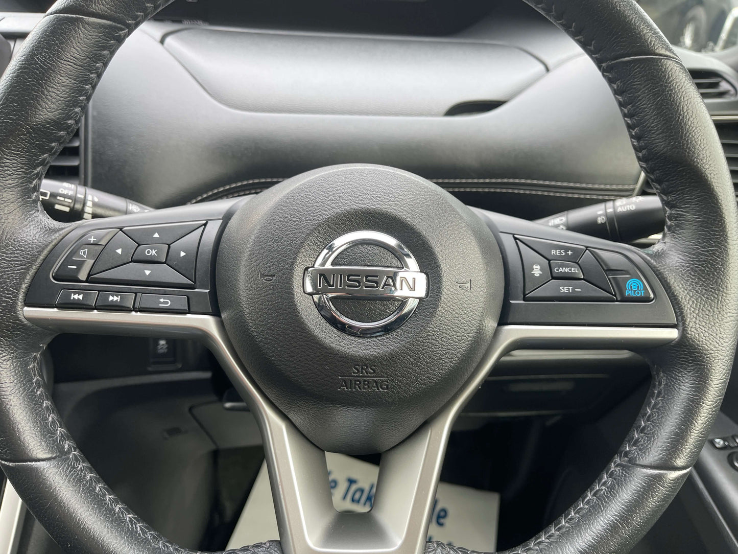 Interior view of the steering wheel in a 2016 Nissan Serena with control buttons and Nissan logo.