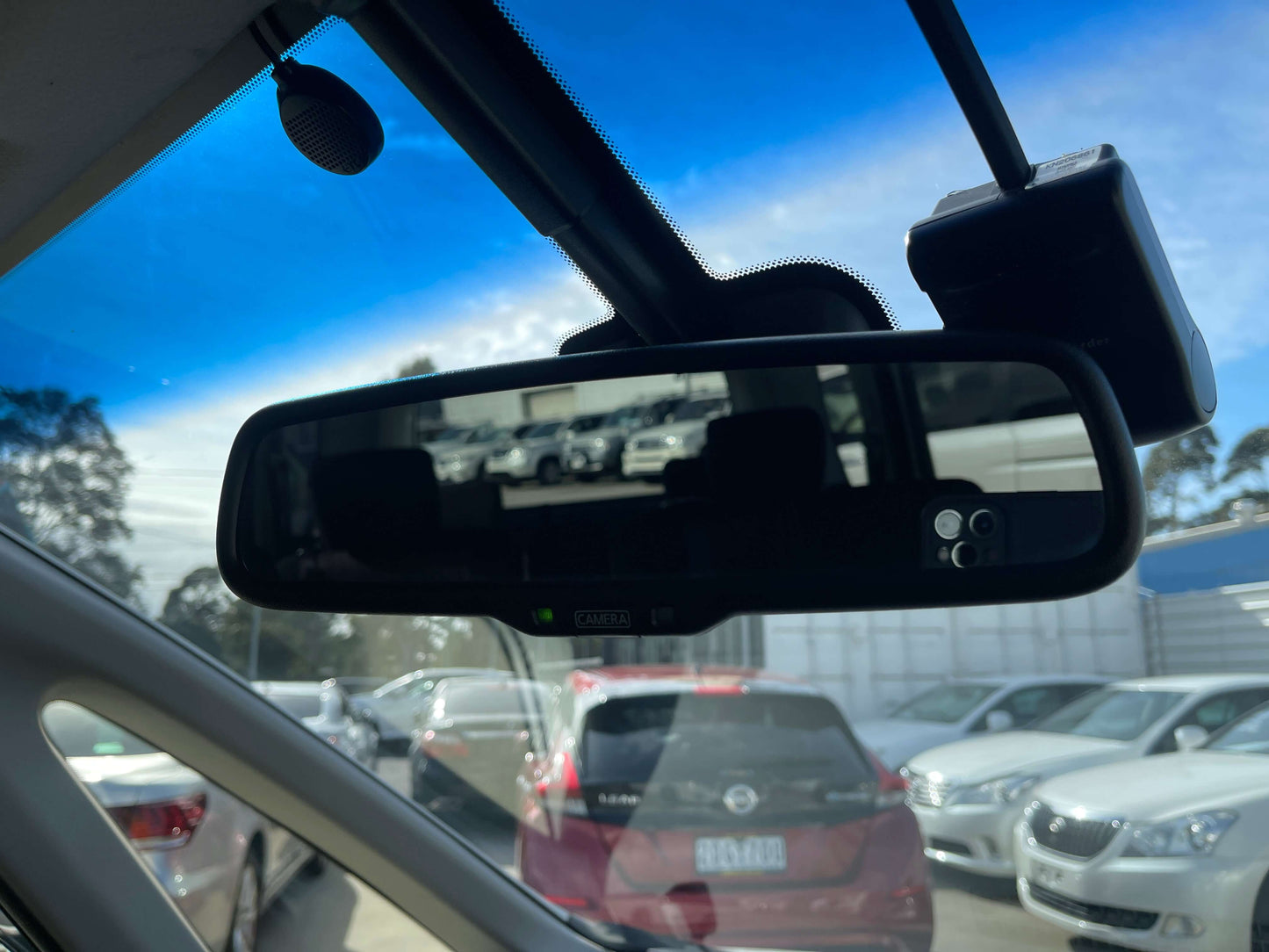 Interior rearview mirror of a 2016 Nissan Serena showing parked vehicles in the background.