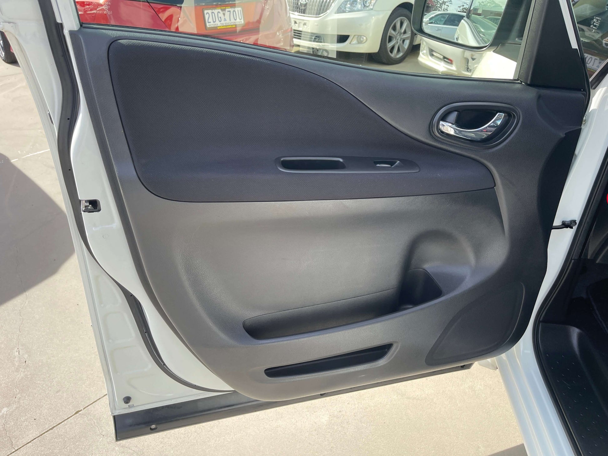 Interior door panel of a 2016 Nissan Serena, showcasing sleek design and functional handle.