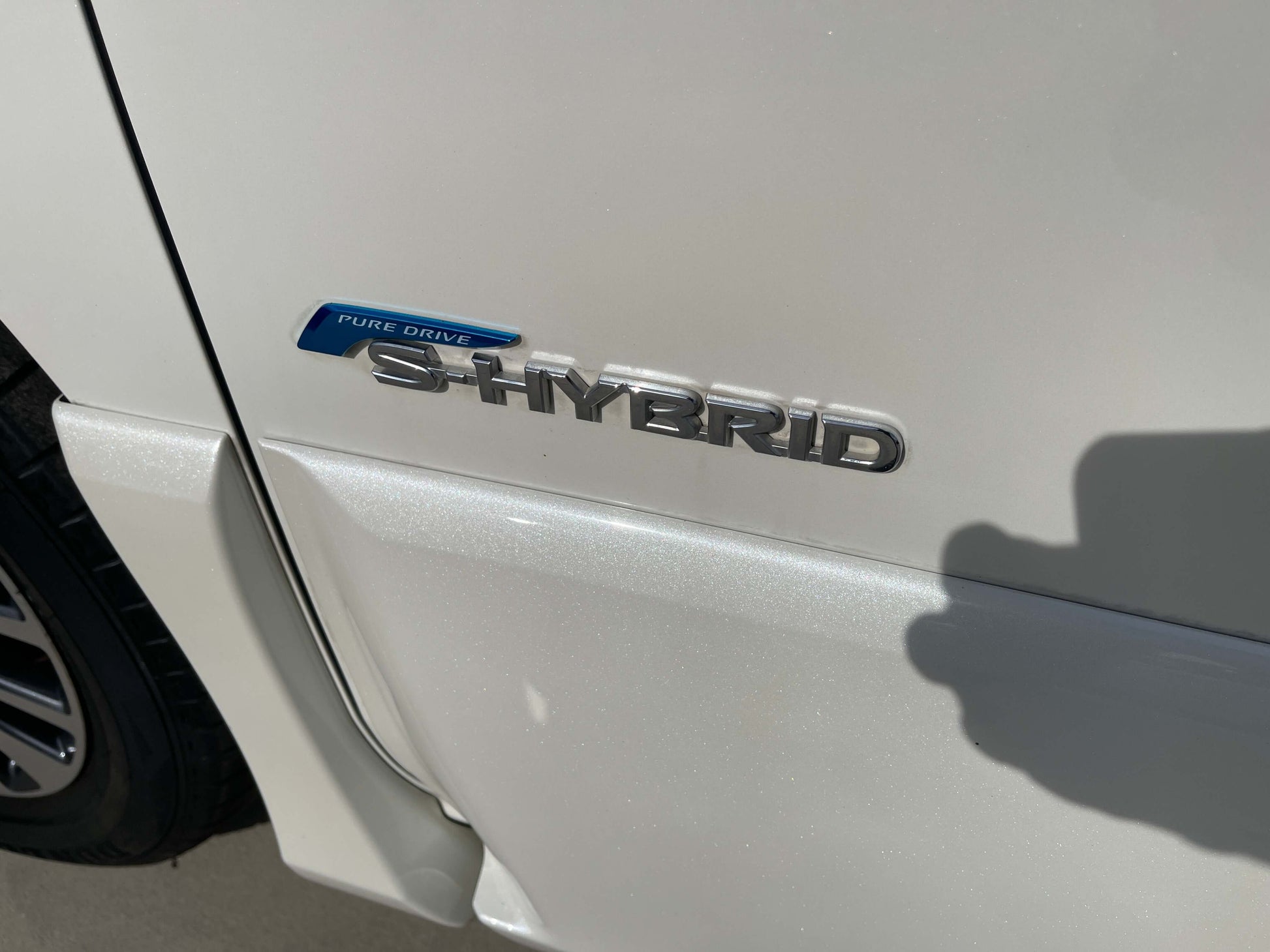 2016 Nissan Serena S-Hybrid badge on white car, showcasing efficient hybrid technology.