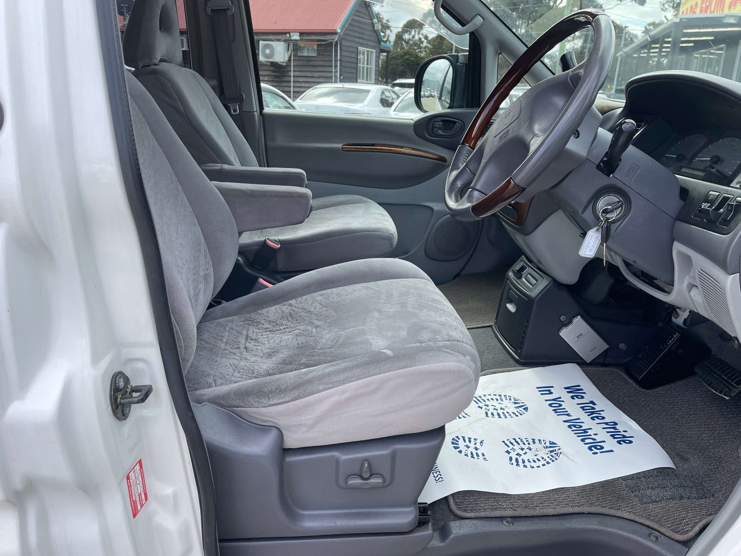 Interior view of 2006 Mitsubishi Delica showing gray seats and dashboard details, highlighting comfort and space