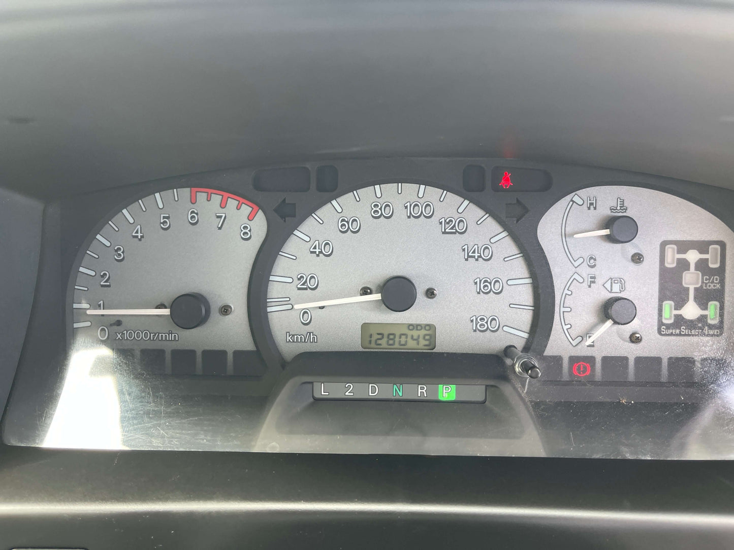 Dashboard display of a 2006 Mitsubishi Delica showing speedometer, tachometer, and odometer reading 128,043 km.