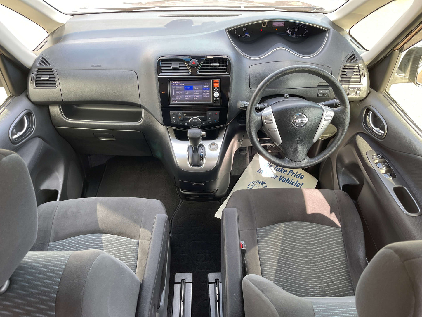 Interior view of the 2016 Nissan Serena with dashboard, steering wheel, and seating layout.