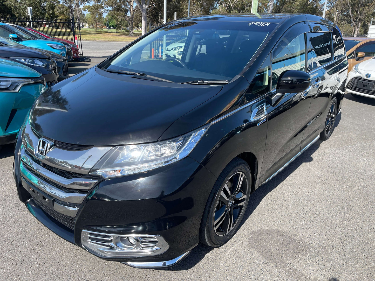 2016 Honda Odyssey 2.0 Hybrid Absolute Honda Sensing in black parked outdoors, showcasing sleek design and modern features.