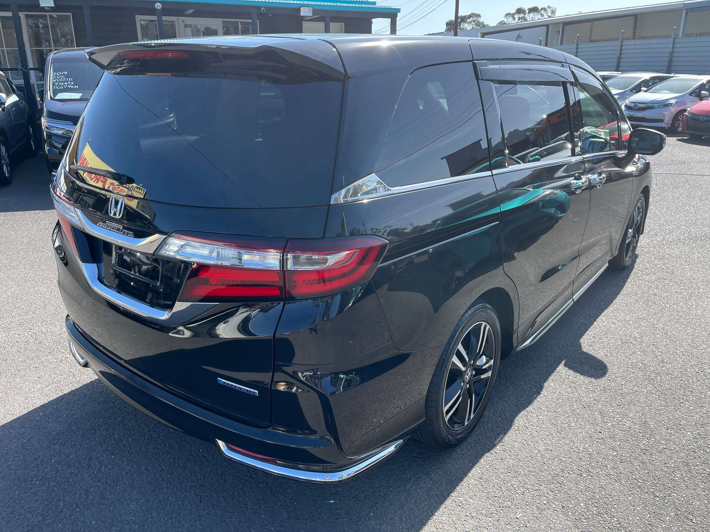 2016 Honda Odyssey 2.0 Hybrid in black color parked, showcasing its sleek design and spacious rear view.