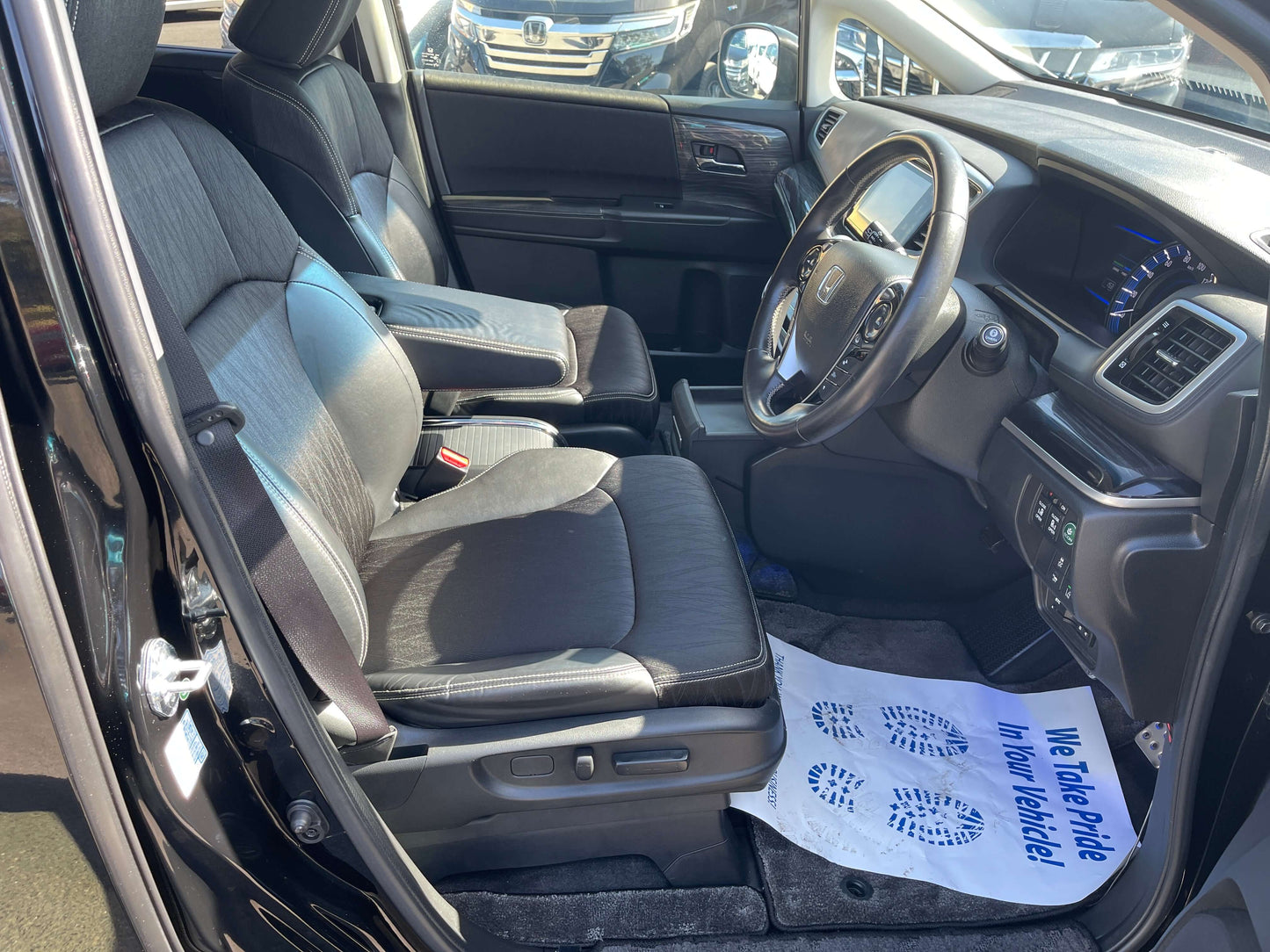 Interior view of a 2016 Honda Odyssey 2.0 Hybrid showcasing front seats and dashboard with modern design.