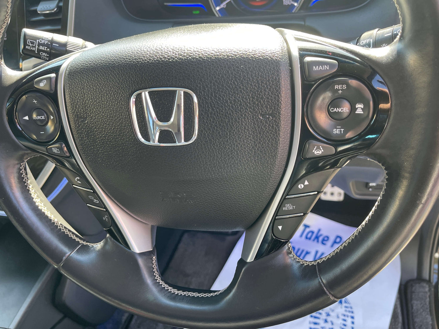 2016 Honda Odyssey 2.0 Hybrid steering wheel with control buttons featuring Honda logo and advanced features display.