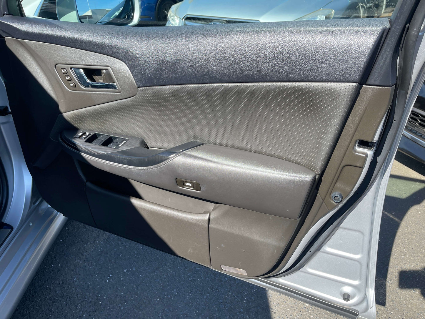 Interior view of the 2009 Toyota Crown V6 3.5L Hybrid luxury sedan door panel showing controls and upholstery.