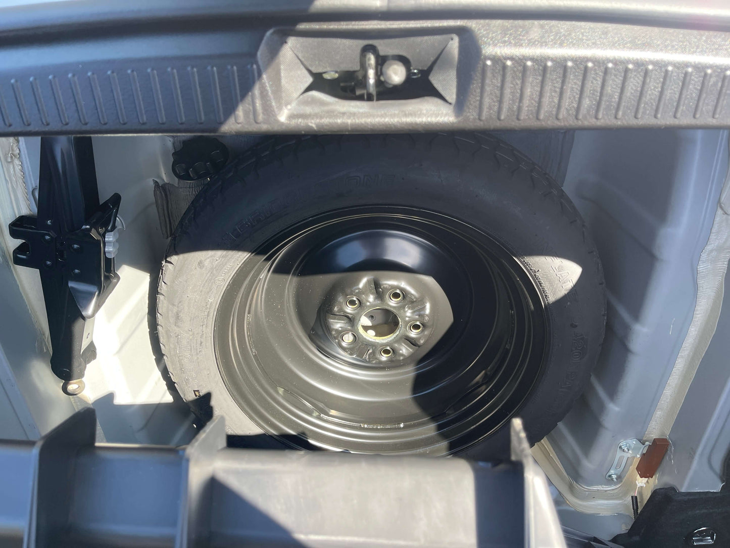 2009 Toyota Crown V6 3.5L Hybrid Spare tire and jack stored in the trunk of a vehicle, showcasing the interior storage design.
