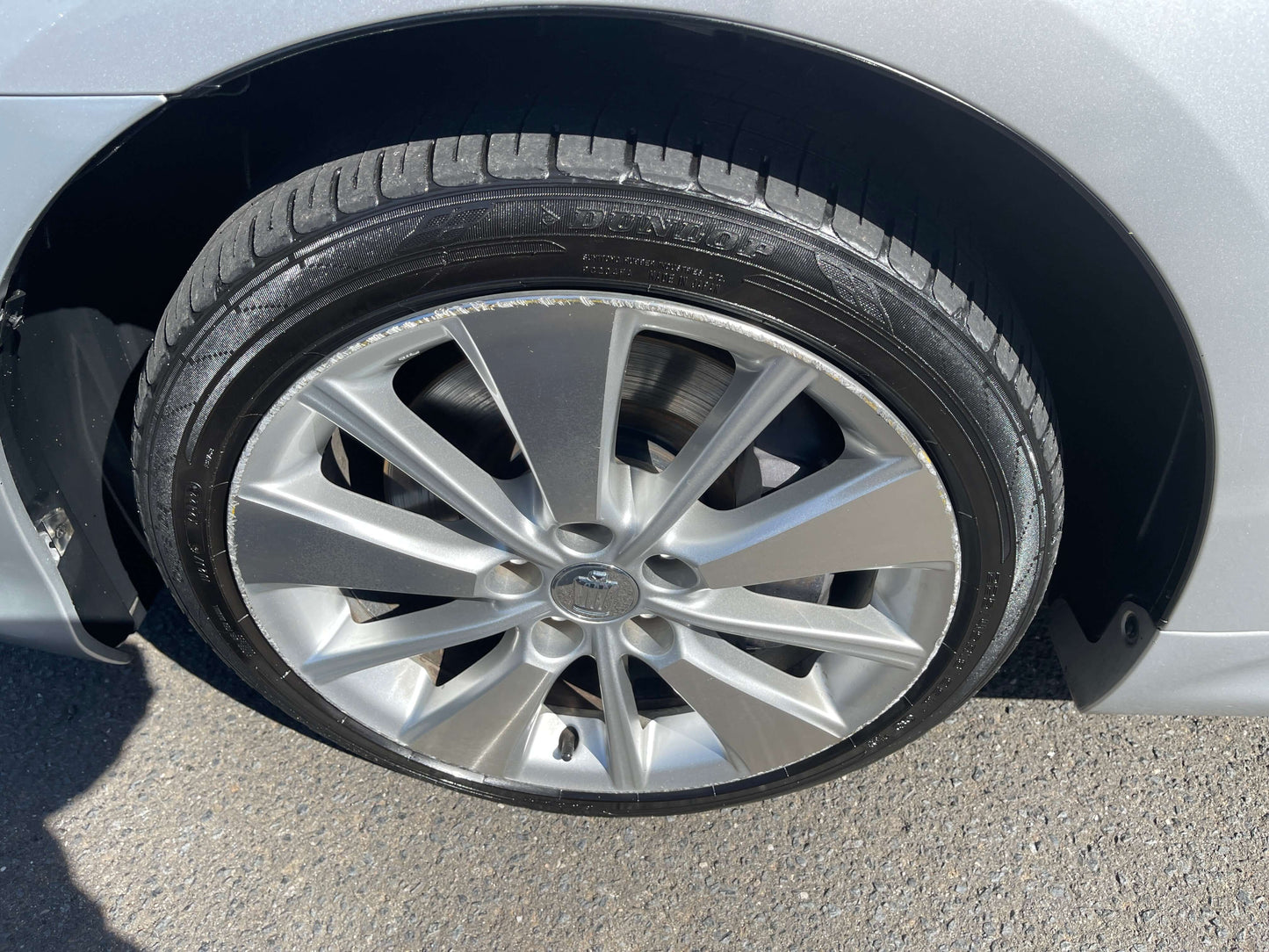 Close-up of a silver alloy wheel with a tire on a 2009 Toyota Crown V6 3.5L Hybrid, showcasing the detailed design.