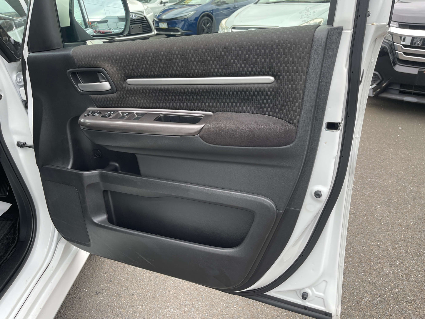 Interior view of the door panel of a 2018 Honda Honda Stepwgn 2.0 Spada Hybrid, showcasing controls and fabric trim.