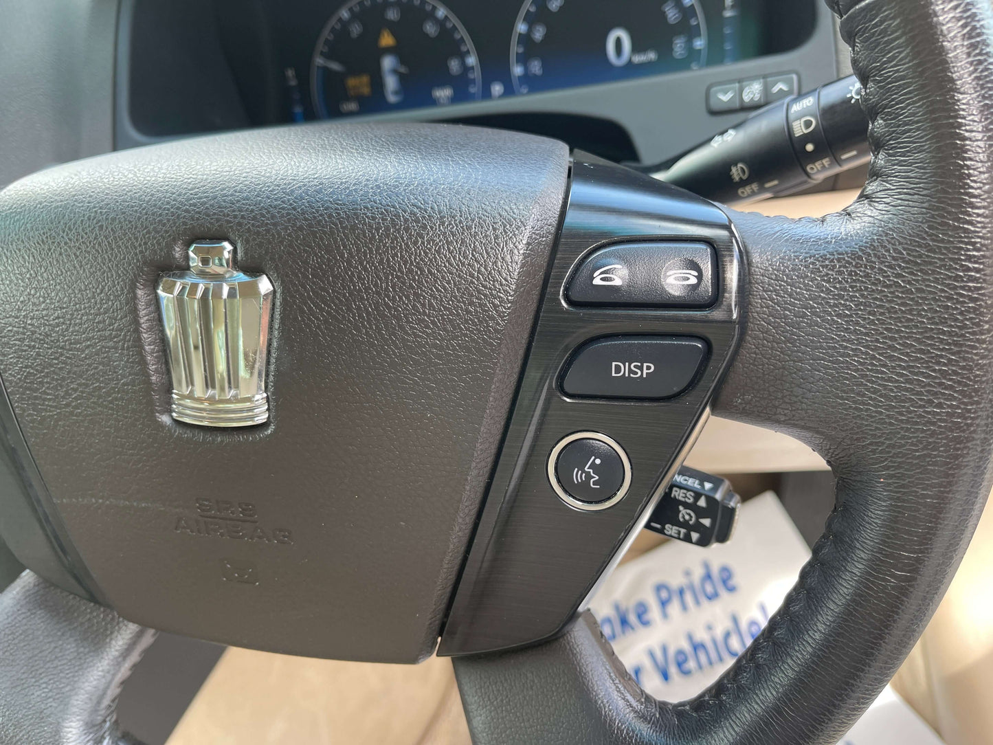 Close-up of the steering wheel buttons in a 2009 Toyota Crown V6 3.5L Hybrid Luxury Sedan, showcasing luxury features.