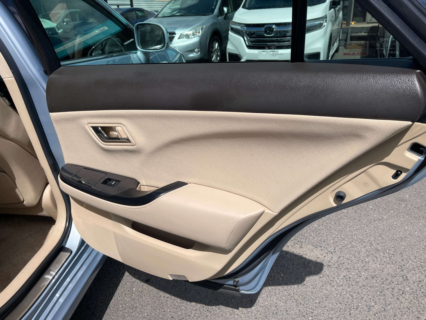 Interior view of the door panel of a 2009 Toyota Crown V6 3.5L Hybrid Luxury Sedan, featuring beige upholstery and controls.