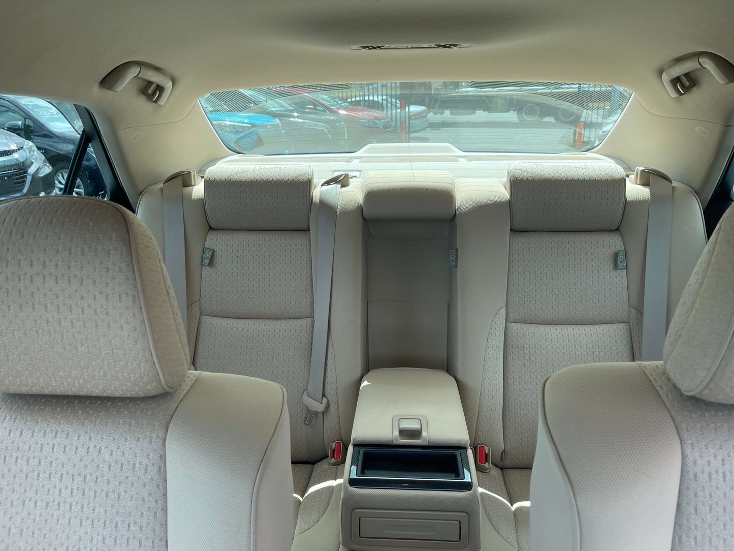 Interior view of the backseat of a 2009 Toyota Crown V6 3.5L Hybrid Luxury Sedan showing plush upholstery and spacious seating.