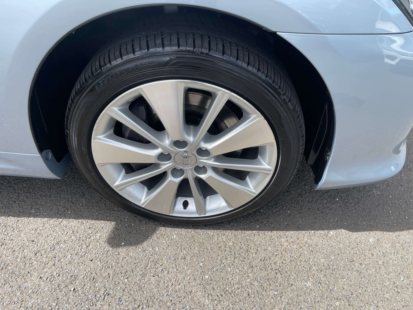 Close-up view of a 2009 Toyota Crown V6 3.5L Hybrid luxury sedan wheel on pavement.