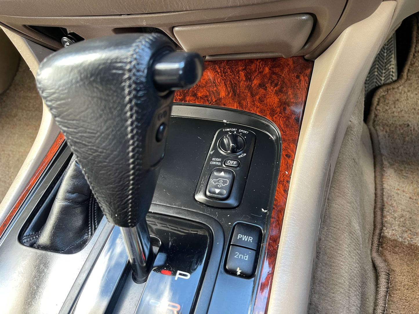 Interior console of a 1998 Toyota Land Cruiser 100 VX Limited showing gear shifter and control panel.