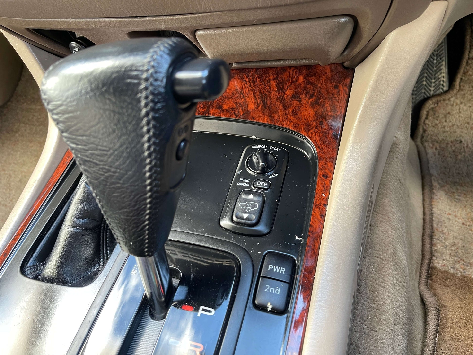 Interior console of a 1998 Toyota Land Cruiser 100 VX Limited showing gear shifter and control panel.
